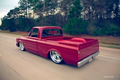 Lowered red pickup driving down highway