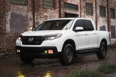 Honda Ridgeline with all-terrain tires next to a brick building